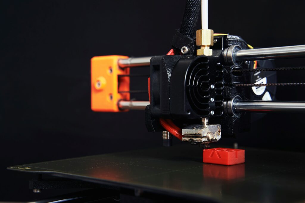 A close up shot of 3d printer, printing a red custom part.